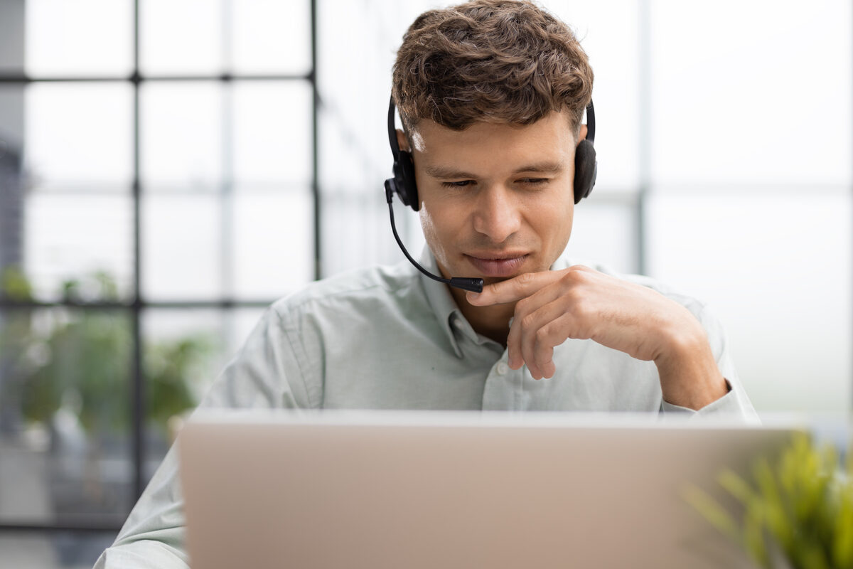 Support agent responding to app store reviews on laptop with headset